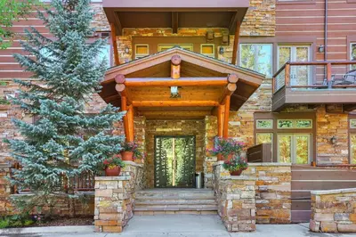 a house with a wooden entry door and a tree at 3056 The Timbers Condo in Keystone