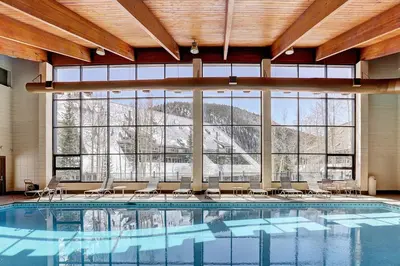 a large swimming pool with chairs and a large window at 2065 The Pines Condo in Keystone