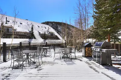 a grill and tables and chairs in the snow at 2065 The Pines Condo in Keystone