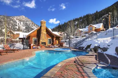 a swimming pool in front of a log cabin at 6509 Settlers Creek Townhomes in Keystone