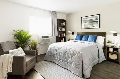 a bedroom with a bed and a chair and a window at InTown Suites Extended Stay Denver - Havana Street in Aurora