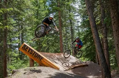 two people on bikes jumping over a wooden ramp at Plaza 1407 in Keystone