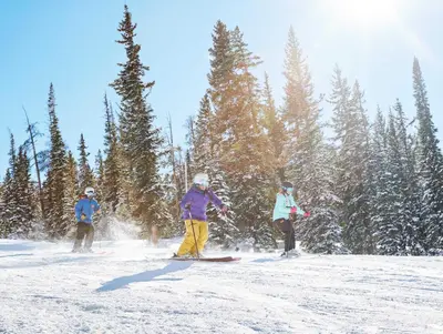 three people are skiing down a snow covered slope at Red Hawk 2272 in Keystone