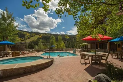 a swimming pool with a table and chairs and a patio at River Run Village 2 Bedroom Condo - 100 Yards To Slopes, Pool, Hot Tub Access in Keystone