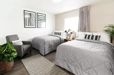 a bedroom with two beds and a chair at InTown Suites Extended Stay Denver - Englewood in Englewood