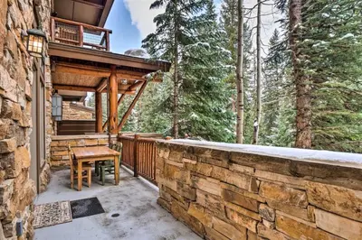 a patio with a wooden table on a stone wall at Ski-In, Ski-Out 1 Bedroom Plus Murphy At The Timbers in Keystone