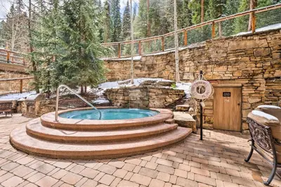 a hot tub in a patio with a stone wall at Ski-In, Ski-Out 1 Bedroom Plus Murphy At The Timbers in Keystone