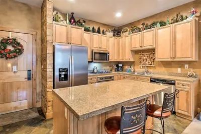 a kitchen with wooden cabinets and a stainless steel refrigerator at Ski-In, Ski-Out 1 Bedroom Plus Murphy At The Timbers in Keystone