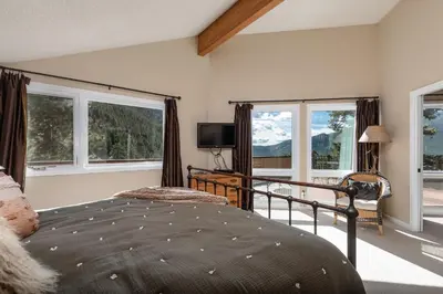 a bedroom with a bed and windows and a television at Cedar Upper Condominium 3 Bedroom condo in Estes Park