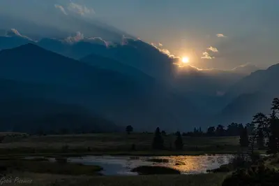 a sunset in the mountains with a river at The Twin Owls 21A Condo in Estes Park
