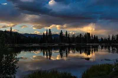 a view of a lake with trees and a cloudy sky at Sheep Mountain 20B Condo in Estes Park
