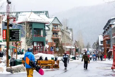 a group of people walking down a street with a snowboard at 1 Bedroom Silvermill Rental In River Run Village Steps From The River Run Gondola in Dillon