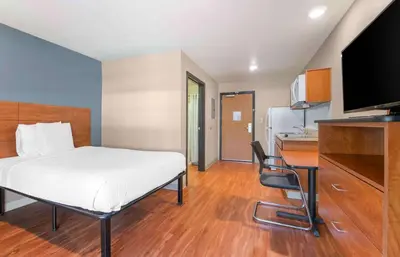 a bedroom with a bed and a desk and a kitchen at Extended Stay America Suites - Denver - Airport in Aurora