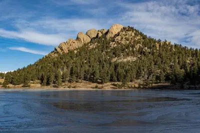 a mountain with trees in front of a body of water at Starlight In The Rockies in Estes Park