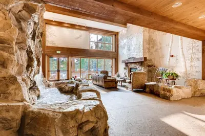 a large living room with a large stone wall at 3 Bedroom Mountain View Condo In River Run Village Just 75 Yards From The Summit Express Gondola in Keystone