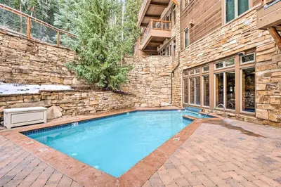 a swimming pool in front of a brick building at Premier 3 Bedroom Timbers Ski In, Ski Out Vacation Rental At The Timbers With The Best Access To Skiing In Keystone in Keystone