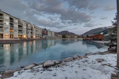a view of a river with buildings and snow at Lakeside 1481 by SummitCove Lodging in Keystone