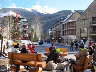 a group of people sitting on benches in a town with a christmas tree at 3 Bedroom Mountain Condo In River Run Village With Expansive Mountain Views And Walking Distance To Ski Slopes in Keystone