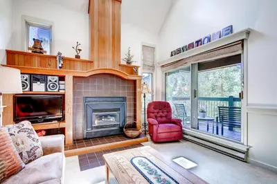 a living room with a fireplace and a red chair at Hot Tub and Grilling Area Keystone Townhome! in Keystone