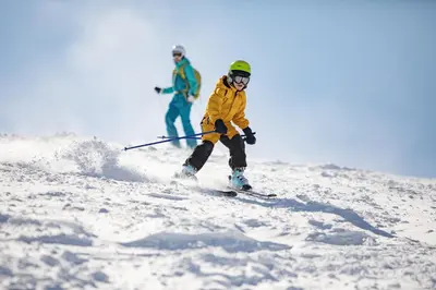 two people are skiing down a snow covered slope at Trailhead Lodge One Bedroom 801 condo in Winter Park