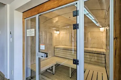 a glass door to a cell with two benches inside at Cozy Fraser Mtn Retreat with Shuttle to Winter Park in Fraser