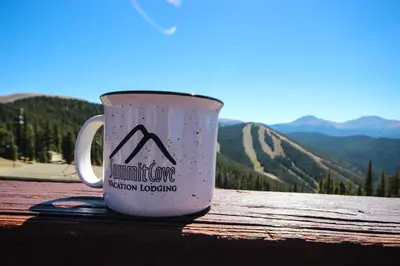 a coffee mug sitting on a table with mountains in the background at Alders 46 by SummitCove Lodging in Keystone