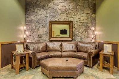 a brown leather couch in a room with a stone wall at Arapahoe Lodge by Summit County Mountain Retreats in Keystone
