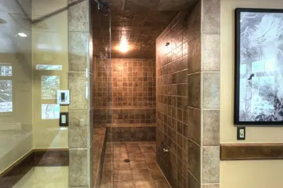 a walk in shower in a bathroom with brown tile at Lone Eagle by Summit County Mountain Retreats in Keystone