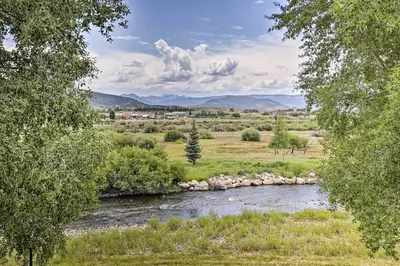 a river in the middle of a field with trees at Fish, Hike and Ski Riverfront Granby Cabin! in Granby