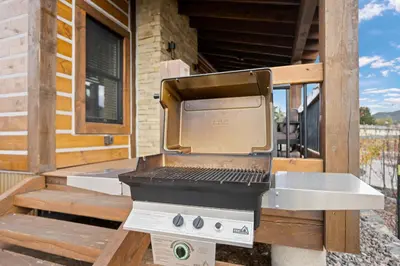 a grill sitting on a porch of a house at Chic Lakefront Cabin - Unbeatable Views! Jacuzzi, Two Patios, Indoor/Outdoor Fireplace in Estes Park