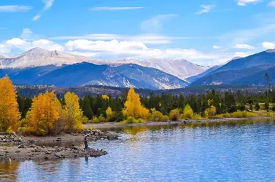 a person standing on the shore of a river with mountains at Buffalo Woods 216 - Wildernest in Silverthorne