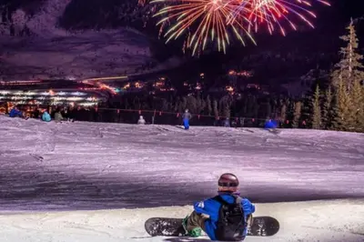 a person on a snowboard sitting in the snow with fireworks at Buffalo Woods 216 - Wildernest in Silverthorne