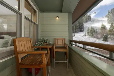 a porch with two chairs and a bed and a window at Beautiful Zephyr Mountain Lodge condo with Slope Base View condo in Winter Park