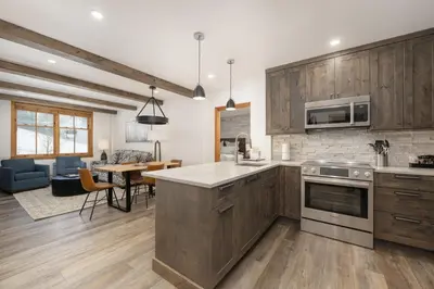 a kitchen with wooden cabinets and a living room at Beautiful Zephyr Mountain Lodge condo with Slope Base View condo in Winter Park