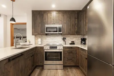 a kitchen with wooden cabinets and a stainless steel appliance at Beautiful Zephyr Mountain Lodge condo with Slope Base View condo in Winter Park
