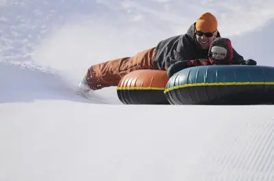 a man riding on a tube in the snow at Bear Trail townhouse in Winter Park
