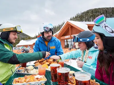 a group of people sitting around a table eating food at Luxurious 2 BR in River Run Village with Ski in ski out, Kids Ski Free condo in Dillon