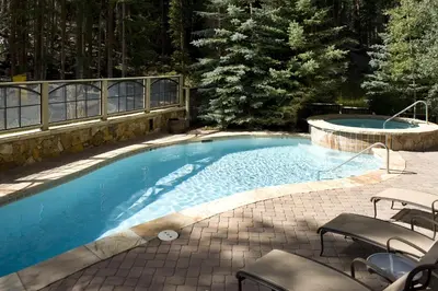 a large swimming pool with chairs next to a patio at Luxurious 3 BR in River Run Village Featuring Ski in, ski out condo in Dillon