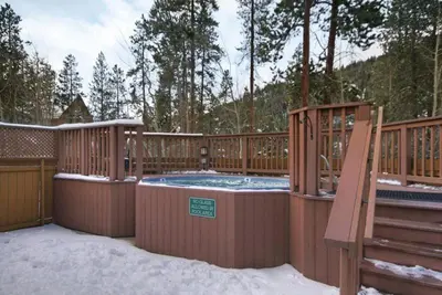 a hot tub on a deck with snow on the ground at Charming Condo Nestled In The East Keystone Resort Neighborhood, Shuttle To Ski Slopes, Outdoor Pool And Hot Tub in Dillon
