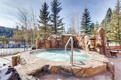 a small pool with a rock wall around it at Beautiful 2 Bedroom Mountain Condo In River Run Village With Hot Tub Access And Walking Distance To The Gondola in Keystone