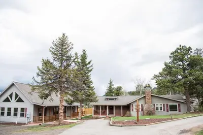 a white house with trees in front of it at Twin Owls Lodge, Great for families Master bedroom, Loft, full kitchen, Dogs OK in Estes Park