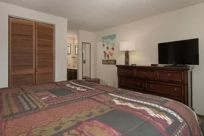 a bedroom with a bed and a dresser with a flat screen tv at Beaver Village Unit #0623 in Winter Park