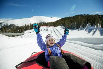 a woman is laying in the snow on a snowboard at Silver Mill 8167 - 1Br-Walk to Slopes! Kids Ski Free! condo in Keystone