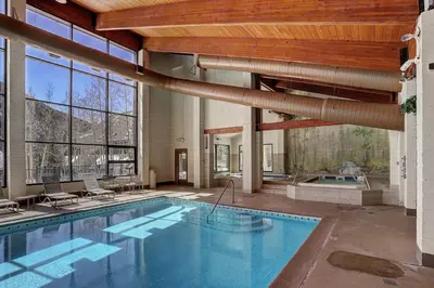 a large swimming pool in a building with a large window at 2056 The Pines condo in Keystone